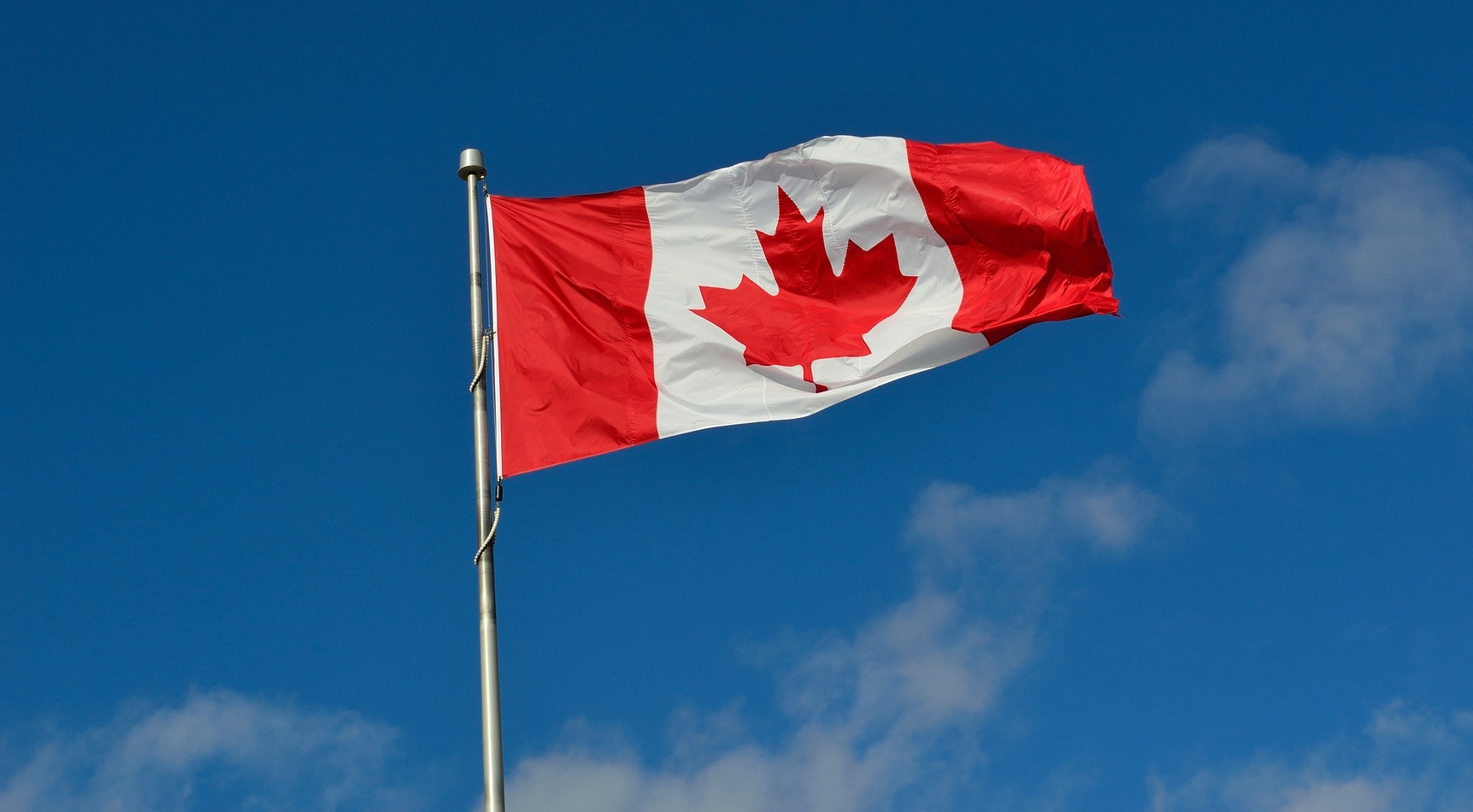 Canadian flag blowing in the wind against a blue sky