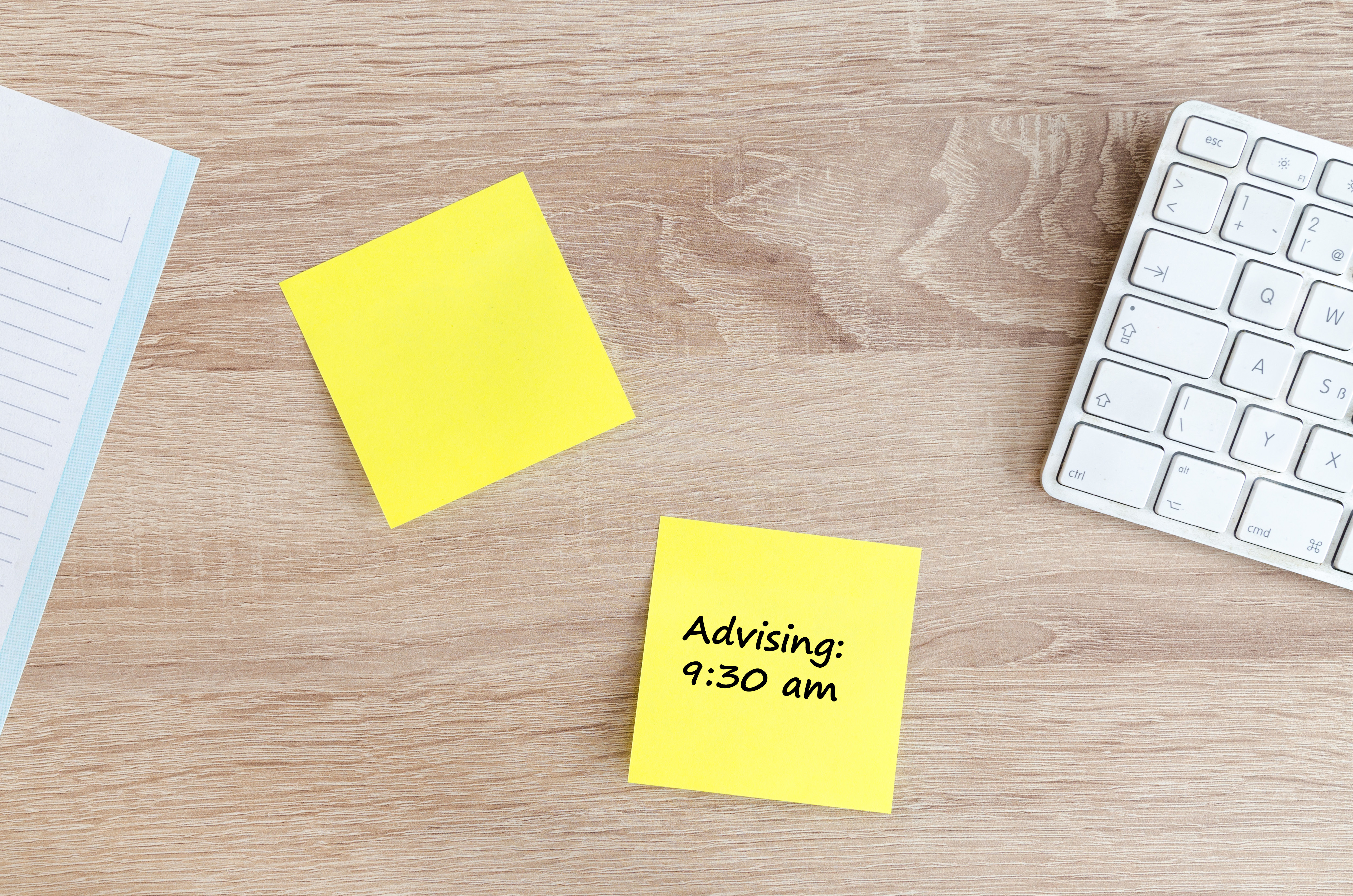 white keyboard on a wooden desk top with yellow post-it notes